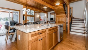 A modern kitchen with wooden cabinetry, a granite countertop, and a stainless steel refrigerator.