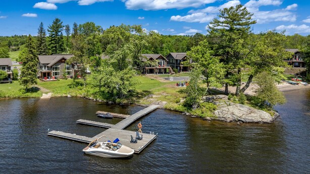 A lakeside resort with docked boats, a pier, and cabins surrounded by trees.