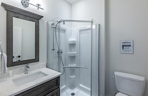 Un baño moderno con ducha acristalada, lavamanos de mármol y inodoro blanco.