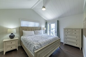 Un dormitorio con cama, mesitas de noche, cómoda y ventana con persianas.