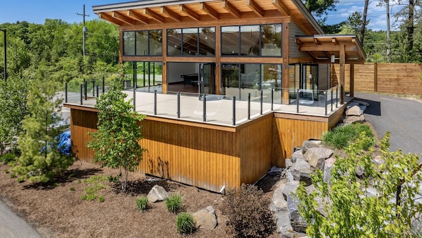 Una cabaña de madera moderna con amplios ventanales, una terraza y un entorno natural.