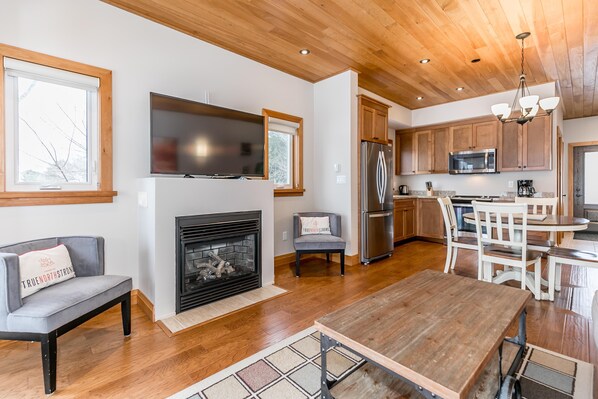 A spacious living room with a fireplace, a dining area, and a kitchen with wooden cabinets and stainless steel appliances. - 2 bed 1.5 bath Villa on Lake Muskoka (Bracebridge)