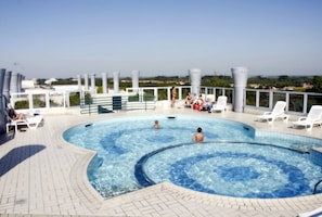 A rooftop swimming pool with lounge chairs and a view of the city.