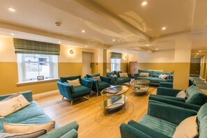 A spacious living area with multiple sofas and armchairs, a coffee table, and a large window providing natural light.