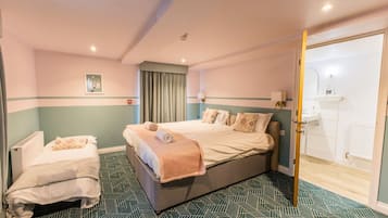 A hotel room with two beds, a bathroom, and a view of the outside.