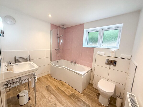 A bathroom with a bathtub, toilet, sink, and a window.