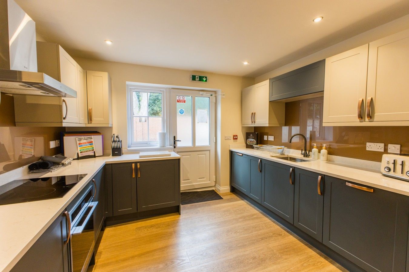 A modern kitchen with grey cabinets, a white countertop, and a stainless steel range hood.