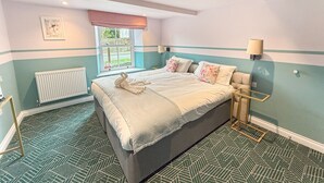 A bedroom with a bed, a window with a view, a radiator, and a patterned floor. - Breckland Thatched Cottage: Hot Tub, 8 Cozy Rooms, Spacious Lounge (Hockwold cum Wilton)