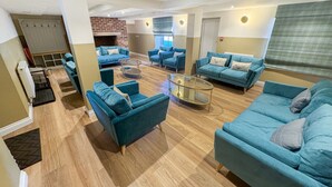 A spacious living area with multiple blue sofas and a glass coffee table. - Breckland Thatched Cottage: Hot Tub, 8 Cozy Rooms, Spacious Lounge (Hockwold cum Wilton)