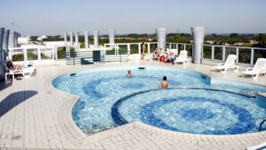 Ein Pool auf dem Dach mit Liegestühlen und Blick auf die Stadt.