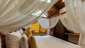 A bedroom with a canopy bed, a wooden headboard, and a stone wall in the background. - Rahta Villa - An Elegant 3BR Villa With BBQ Terrace (Dehradun)