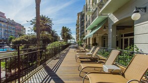 A wooden deck with lounge chairs, a pool, and a view of a cityscape. - Coberturas sofisticadas no IL Campanario Resort ILCTOPM (Florianópolis)