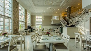 A spacious dining area with high ceilings, large windows, and a staircase leading to an upper level. - Coberturas sofisticadas no IL Campanario Resort ILCTOPM (Florianópolis)