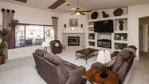 A living room with a fireplace, sofa, coffee table, and television. - Havasu Jamaica S - Pool, Spa, Casita, Central (Lake Havasu City)