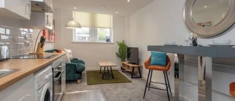 A modern kitchen with a dining area, a small table, and a bar area with stools.