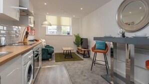 Een moderne keuken met een eethoek, een kleine tafel en een bar met krukken.