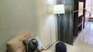 A modern living room with a beige armchair, a floor lamp, and a dark rug.