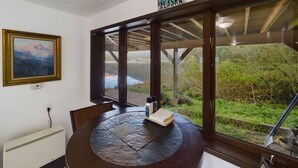Une pièce avec une grande fenêtre, un tableau accroché au mur et une table sur laquelle se trouvent un livre et une bouteille.