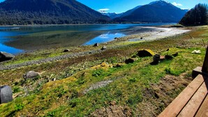Une vue sur le lac, avec des montagnes en arrière-plan, une terrasse en bois et un ciel dégagé.