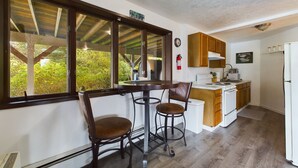 Une cuisine avec des meubles en bois, un réfrigérateur blanc et une fenêtre donnant sur un espace verdoyant.