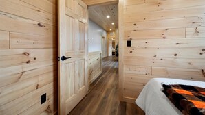 Een houten interieur met een bed, een deur en een gang naar een andere kamer.
