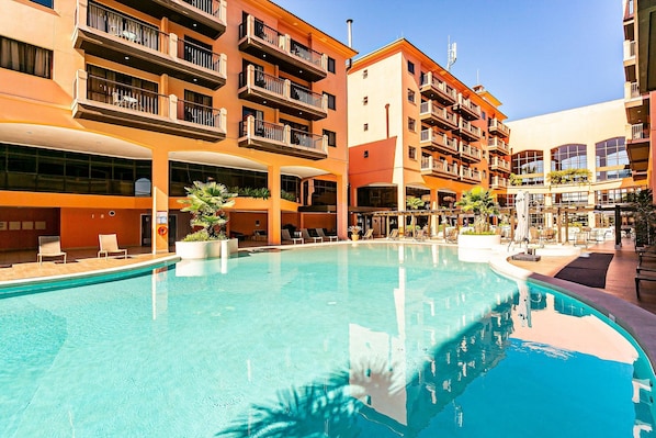 Um hotel com piscina, várias varandas e áreas de estar ao ar livre.