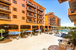 Un hotel de varios pisos con zonas de estar al aire libre, piscina y balcones.
