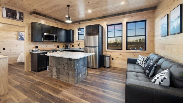 A modern kitchen with a central island, stainless steel appliances, and wooden walls. - Cozy Trailside Lodge #2 (Boonville)
