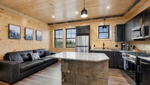 A modern kitchen with a central island, dark cabinetry, stainless steel appliances, and a wooden ceiling. - Cozy Trailside Lodge #2 (Boonville)