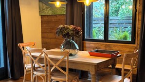 Een houten eettafel met vier stoelen, een vaas met bloemen en een laptop op de tafel.