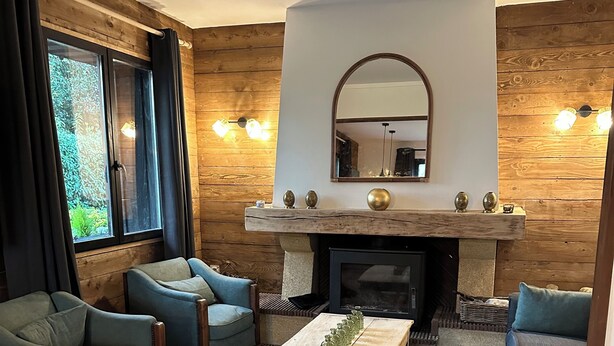 Een gezellige woonkamer met houten wanden, een open haard en comfortabele zitplaatsen.