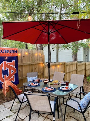Eine Terrasse im Freien mit einem roten Sonnenschirm, einem Esstisch und einer Flagge mit dem Aufdruck 'Auburn Tigers'.