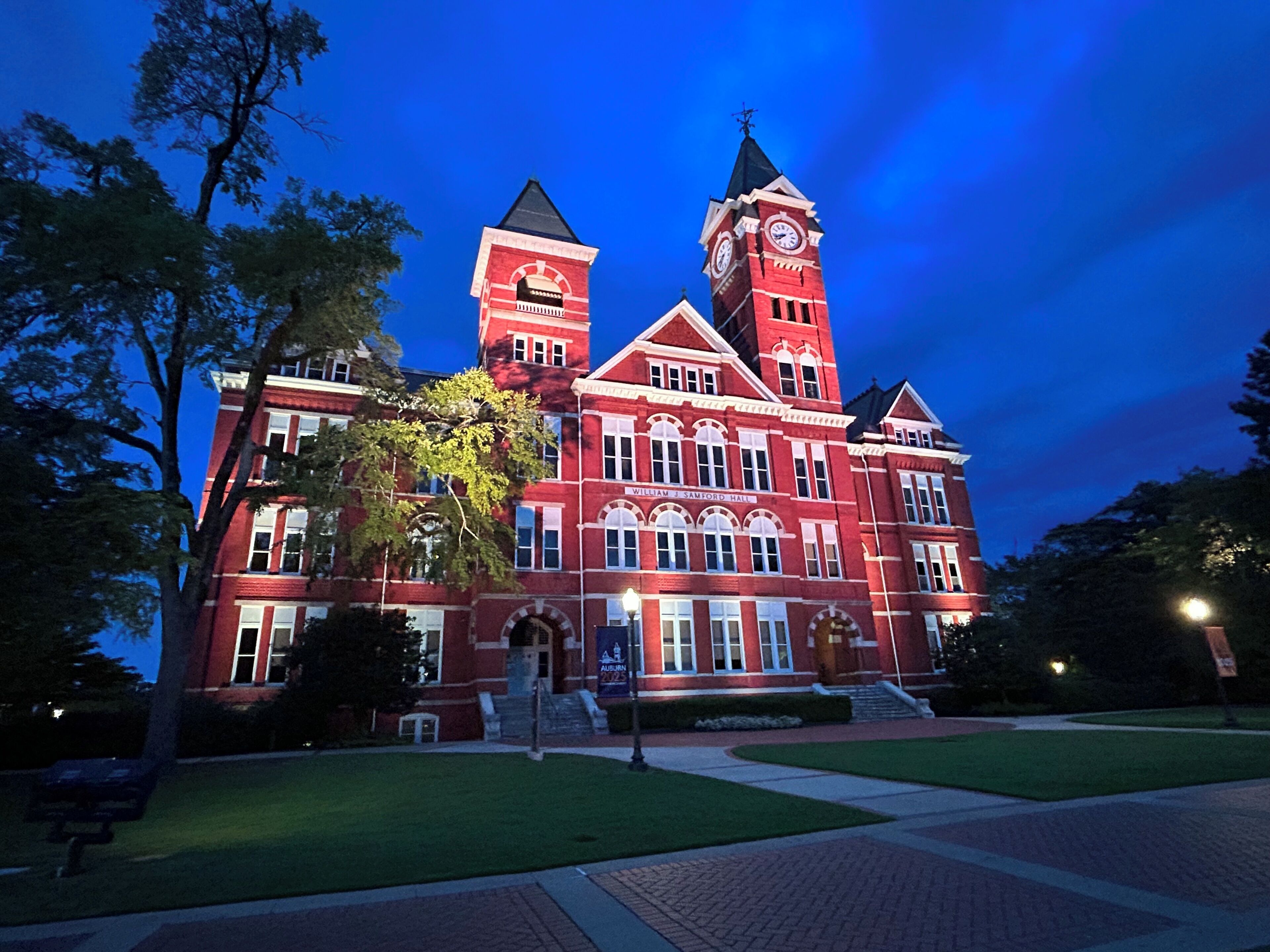 A large red brick building with a clock tower, arched windows, and a sign reading "William J. Samford Hall".