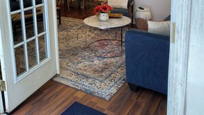 Ein Wohnzimmer mit einem blauen Sofa, einem Couchtisch und einem Essbereich mit orangefarbenen Stühlen.