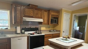 Une cuisine avec des meubles de rangement en bois, un four à micro-ondes, une cuisinière et un lave-vaisselle.
