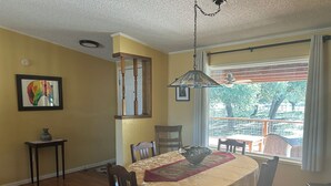 Un coin repas avec une table ronde, des chaises, un vase et un tableau accroché au mur.