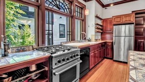 A kitchen with wooden cabinets, a stainless steel refrigerator, a gas stove, and a dishwasher. - Historic Mansion Built in 1896, Pan Am. Expo Era (Buffalo)