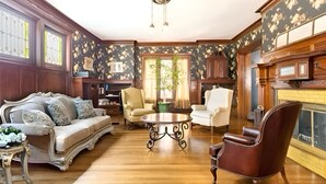 A traditional living room with a wooden floor, a sofa, a coffee table, and a fireplace. - Historic Mansion Built in 1896, Pan Am. Expo Era (Buffalo)