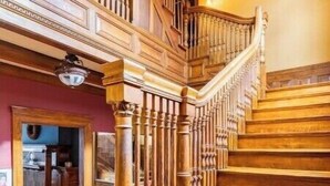 A grand wooden staircase with intricate balusters and a handrail, leading to an upper floor. - Historic Mansion Built in 1896, Pan Am. Expo Era (Buffalo)