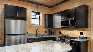 A modern kitchen with granite countertops, stainless steel appliances, and wooden paneling. - Cozy Trailside Lodge #1 and #2 (Boonville)