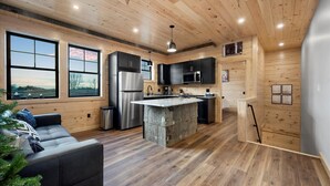 A modern kitchen with wooden walls, a central island, and a built-in oven. - Cozy Trailside Lodge #1 and #2 (Boonville)