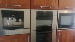 A kitchen with stainless steel appliances, wooden cabinets, and a microwave. - 2 bedroom house near Athy, 45 minutes by train to Dublin (Athy)