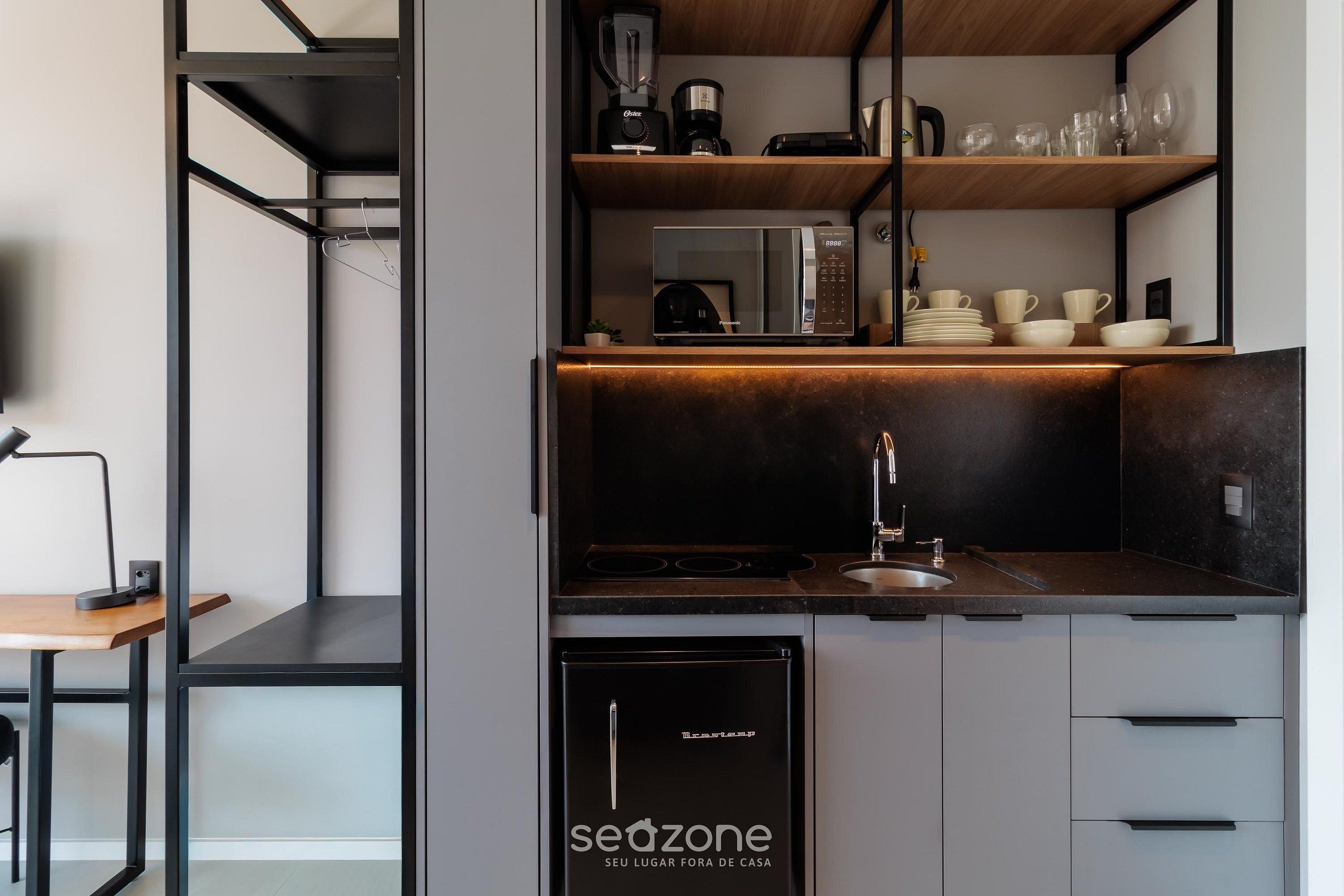 Cozinha moderna com eletrodomésticos embutidos, pia e área de refeições com mesa e cadeira.
