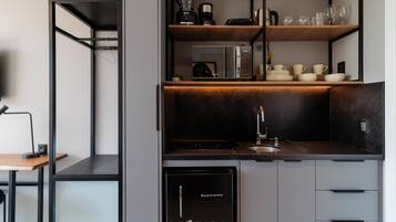Cozinha moderna com eletrodomésticos embutidos, pia e área de refeições com mesa e cadeira.