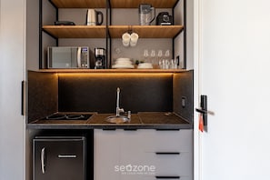 Una kitchenette compacta con estufa integrada, pileta y heladera pequeña.
