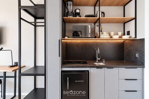 Una cocina compacta con lavavajillas, cafetera y hervidor sobre la encimera.