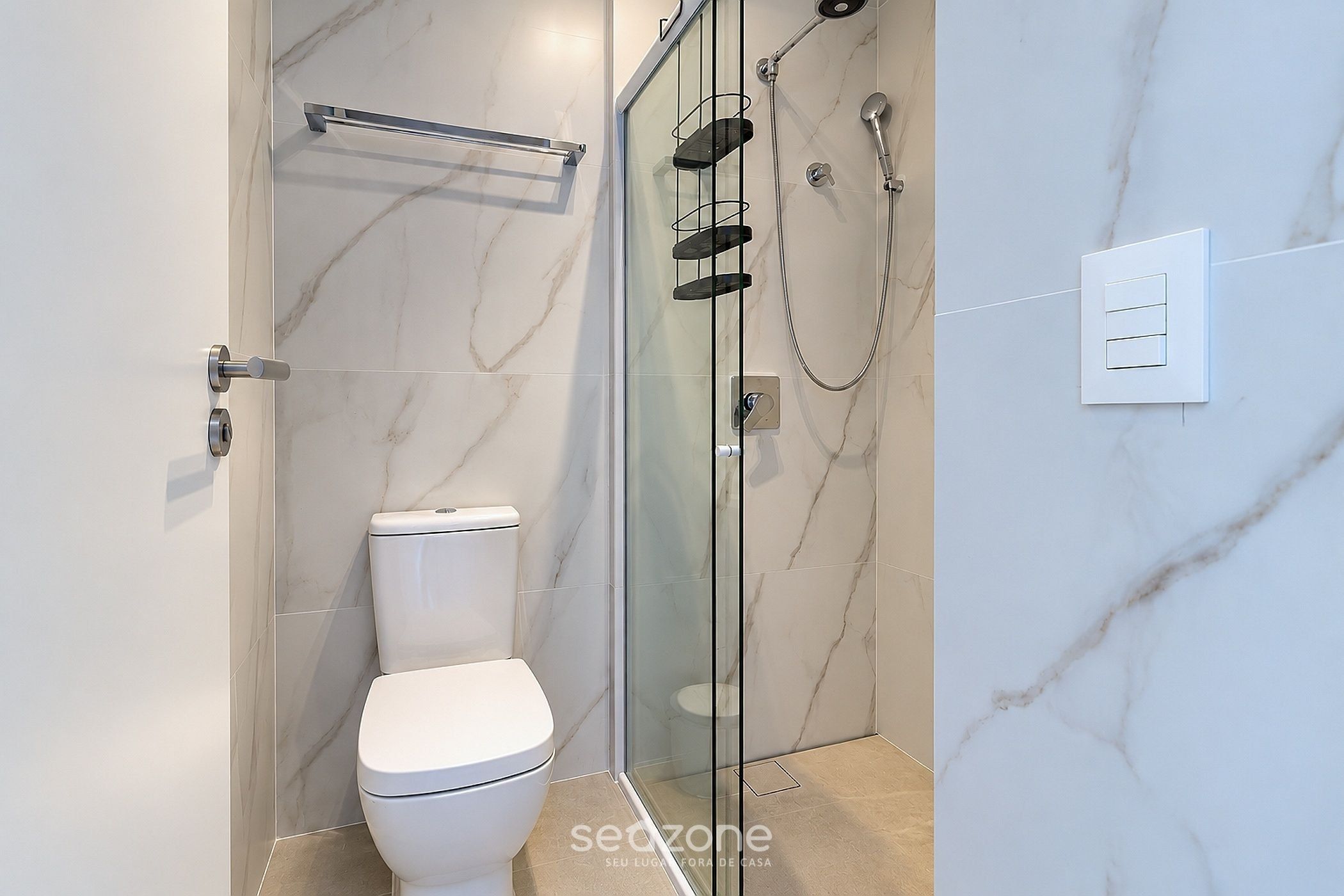 Une salle de bain moderne avec une douche à parois de verre, des toilettes et un porte-serviettes.