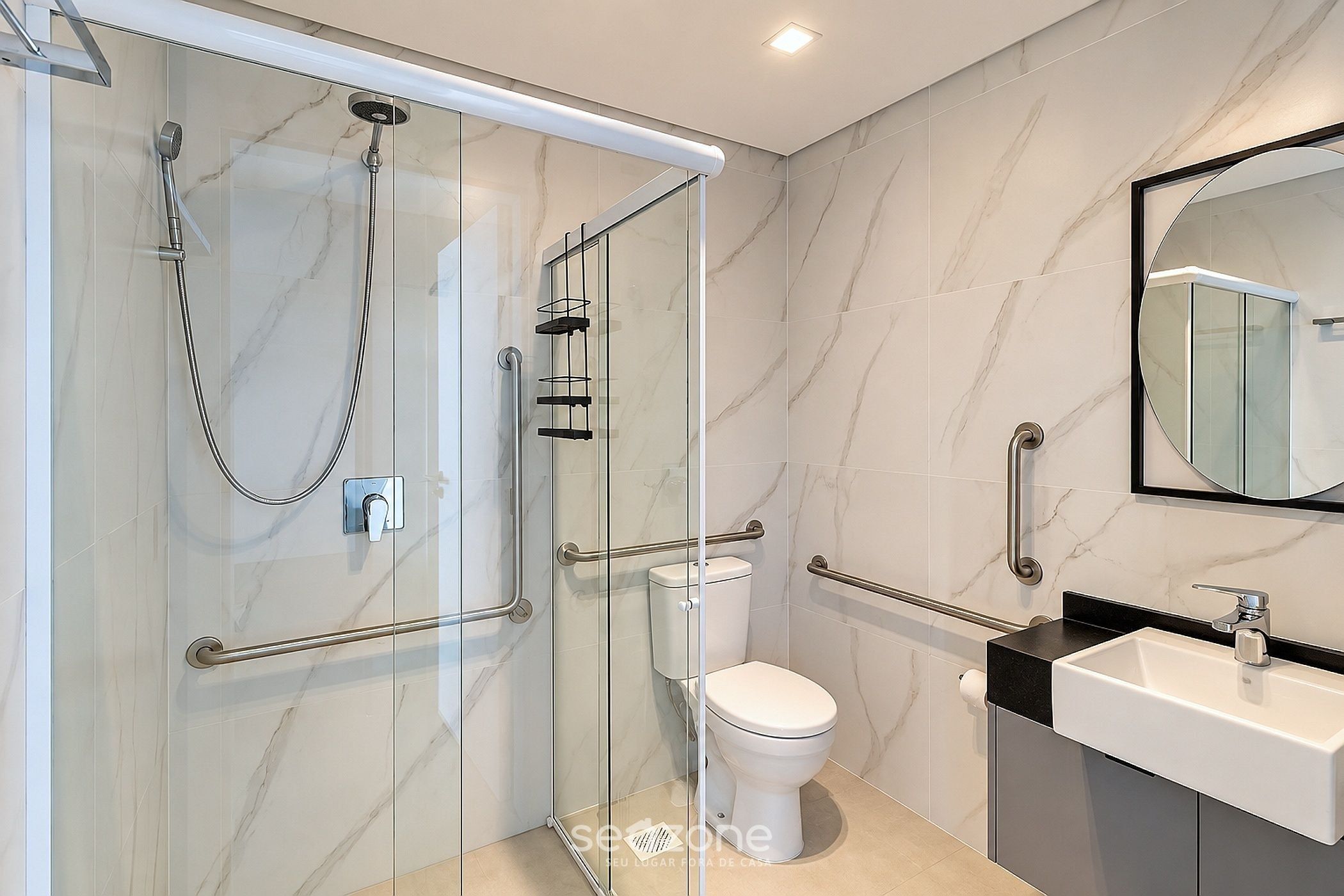Un baño moderno con ducha envuelta en vidrio, un inodoro y un lavamanos con un espejo encima.