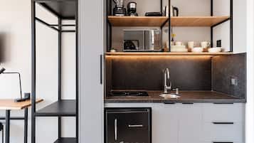 Uma cozinha compacta com lava-louças, cafeteira e chaleira no balcão.