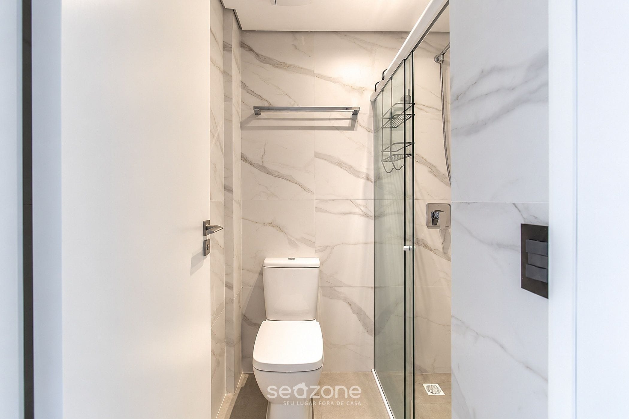Un baño moderno con inodoro, cabina de ducha y paredes de mármol.